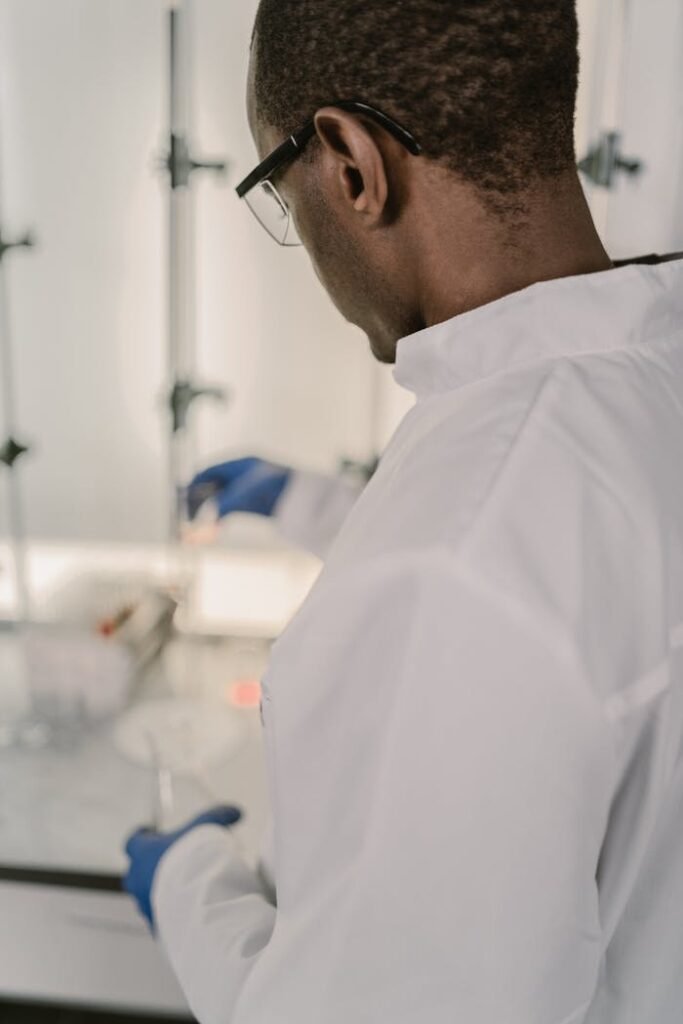 Research scientist in lab coat conducting experiments in a laboratory setting, focused on chemical reactions.